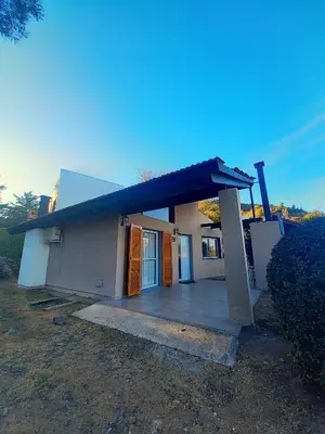 a small white house with a large porch at Cabañas Loma Azul in Villa General Belgrano
