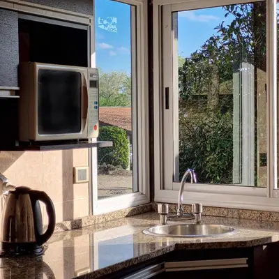 a kitchen with a sink and a microwave and a window at Cabañas Loma Azul in Villa General Belgrano