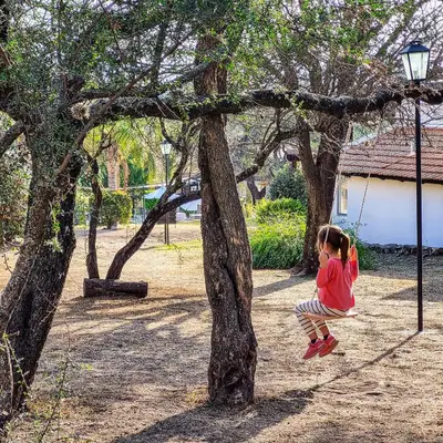 a little girl jumping off of a tree at Cabañas Loma Azul in Villa General Belgrano