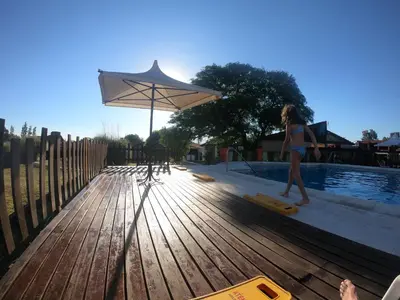 a woman walking next to a pool with an umbrella at Cabañas Loma Azul in Villa General Belgrano