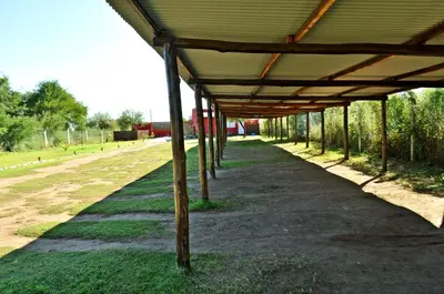 a covered walkway next to a field of grass at Cabañas Las Troncas in Merlo