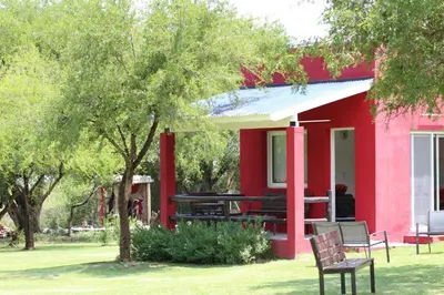 a red house with a picnic table in the yard at Cabañas Las Troncas in Merlo