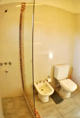 a bathroom with a toilet and a glass shower at Cabañas Las Troncas in Merlo