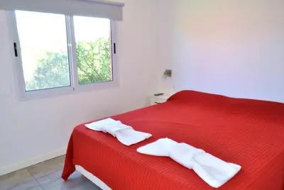 a red bed with two white towels on it at Cabañas Las Troncas in Merlo