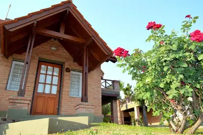 a brick house with a wooden door next to a tree at Cabañas Quilquelen in Merlo