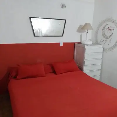 a bedroom with a bed with red sheets and a mirror at TEMPORARIO CORDOBA in Cordoba