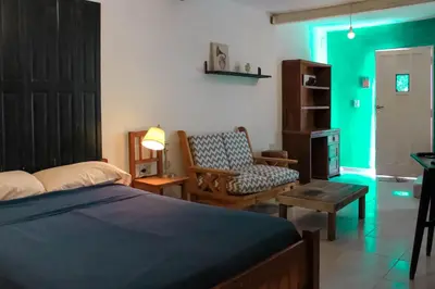a bedroom with a bed and a chair and green light at flia Fortuna in Mina Clavero