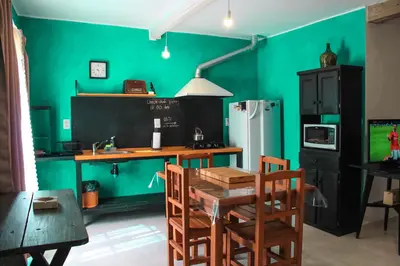 a kitchen with green walls and a table and chairs at flia Fortuna in Mina Clavero