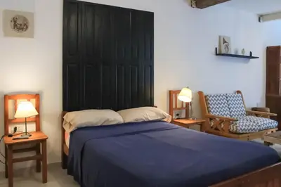 a bedroom with a bed with a black headboard and a chair at flia Fortuna in Mina Clavero