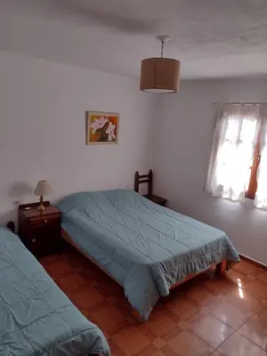 a bedroom with two beds and a night stand and window at Casa Grande in Villa Carlos Paz