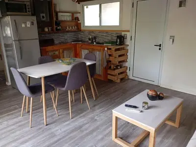 a kitchen with a table and two chairs and a table and a table sidx sidx at Cabañas Piedras del Xanaes, colindantes al río in Villa Los Aromos