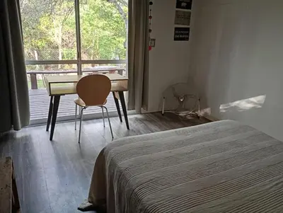 a bedroom with a bed and a desk and a window at Cabañas Piedras del Xanaes, colindantes al río in Villa Los Aromos