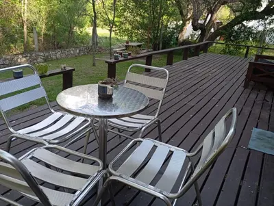 a table and chairs on a wooden deck at Cabañas Piedras del Xanaes, colindantes al río in Villa Los Aromos