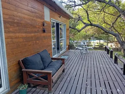 a wooden porch with a couch on a deck at Cabañas Piedras del Xanaes, colindantes al río in Villa Los Aromos