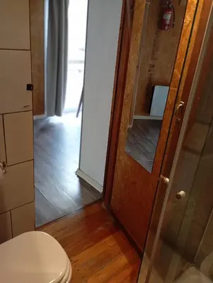 a bathroom with a toilet and a glass door at Cabañas Piedras del Xanaes, colindantes al río in Villa Los Aromos