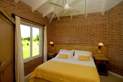 a bedroom with a bed and a brick wall at Arenas Blancas Cabañas & Suites in Nono