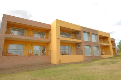 a yellow building with chairs on the balconies of it at Arenas Blancas Cabañas & Suites in Nono