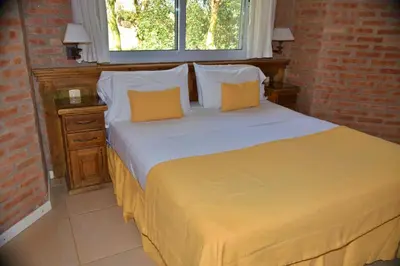 a bedroom with a large bed with two yellow pillows at Arenas Blancas Cabañas & Suites in Nono