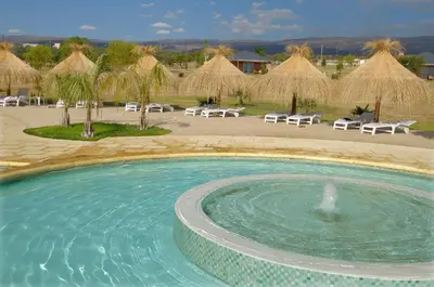 a pool with chairs and umbrellas in a resort at Arenas Blancas Cabañas & Suites in Nono