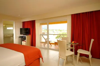 a bedroom with a bed and a table and a balcony at Arenas Blancas Cabañas & Suites in Nono