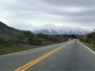a car driving down a road with mountains in the background at departamentos sosa in Mina Clavero