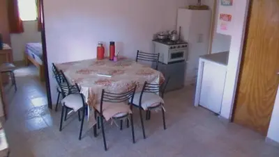 a kitchen with a table and chairs in a room at departamentos sosa in Mina Clavero