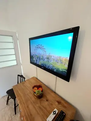 a television on a wall with a bowl of fruit on a table at Rumihuasi Apartamento in Los Reartes