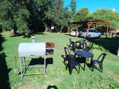 a grill and tables and chairs in a field at DEPARTAMENTOS SOSA in Mina Clavero