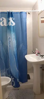 a bathroom with a blue shower curtain next to a sink at Complejo 