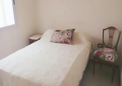 a bed with a pillow and a chair in a room at Departamento Carlos Paz, Centro in Villa Carlos Paz