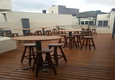 a row of wooden tables and stools on a balcony at Departamento Carlos Paz, Centro in Villa Carlos Paz
