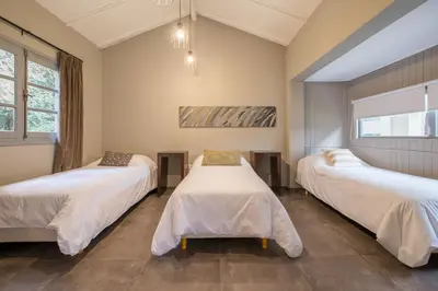 a room with three beds with white sheets at Calina Casa de Huéspedes in Villa General Belgrano