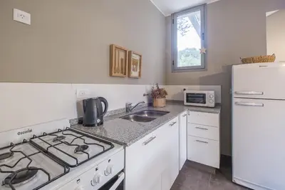 a kitchen with a stove and a sink and a refrigerator at Calina Casa de Huéspedes in Villa General Belgrano