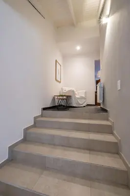 a hallway with stairs with a table and a couch at Calina Casa de Huéspedes in Villa General Belgrano