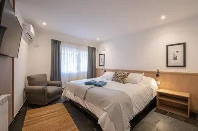 a hotel room with a bed and a chair at Calina Casa de Huéspedes in Villa General Belgrano