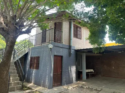 a brick house with a staircase and a tree at Cabañas Los Aromos in Embalse
