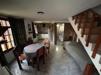 a living room with a table and a staircase at Cabañas Los Aromos in Embalse