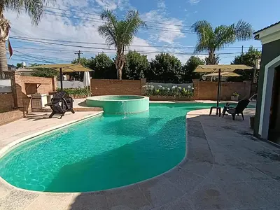 a swimming pool in a yard with chairs and umbrellas at Cabañas Los Aromos in Embalse