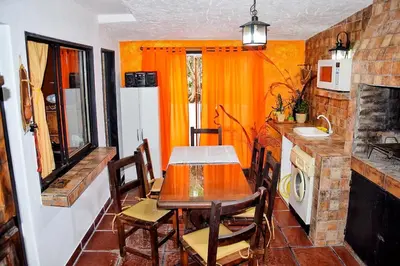 a kitchen with a table and a kitchen with orange walls at CASA FRENTE AL RIO Playas de Oro in Villa Carlos Paz