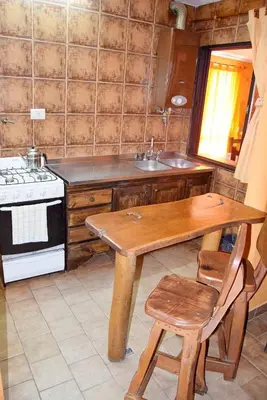 a kitchen with a wooden table and a stove at CASA FRENTE AL RIO Playas de Oro in Villa Carlos Paz