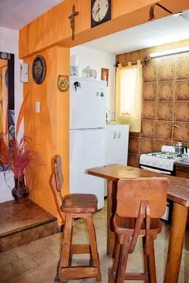 a kitchen with a table and a white refrigerator at CASA FRENTE AL RIO Playas de Oro in Villa Carlos Paz