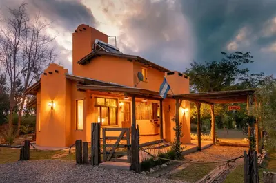 a house with an open door in a yard at Cabañas La Matera in Los Reartes