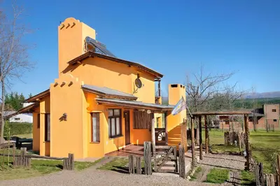 a small yellow house with a fence around it at Cabañas La Matera in Los Reartes