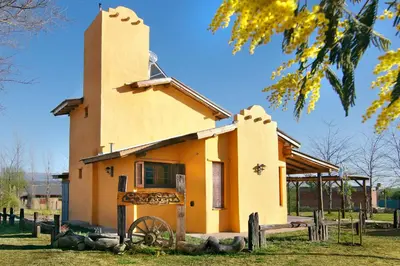 a small yellow building with a wheel in front of it at Cabañas La Matera in Los Reartes