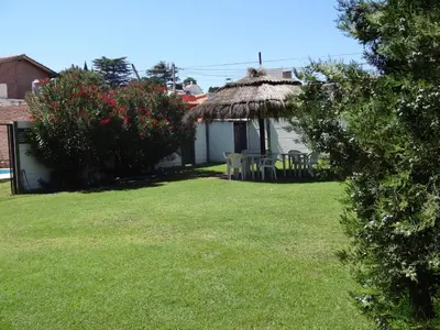 a yard with a grass hut with chairs and flowers at Rincón del Valle in Mina Clavero
