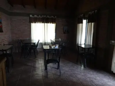 a dining room with tables and chairs and windows at Rincón del Valle in Mina Clavero