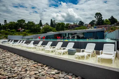 a row of white chairs next to a swimming pool at Domus Lake Resorts in Villa Carlos Paz