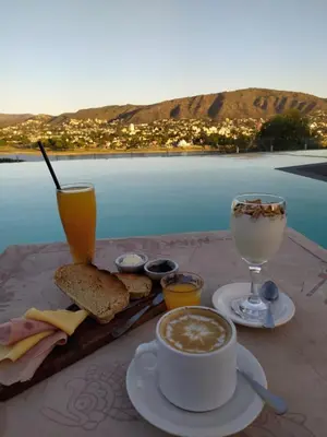 a table with a cup of coffee and bread and a drink at Domus Lake Resorts in Villa Carlos Paz