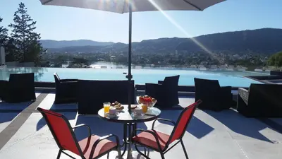 a table with chairs and an umbrella on a patio at Domus Lake Resorts in Villa Carlos Paz