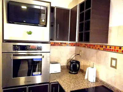 a kitchen with stainless steel appliances and black cabinets at Altos de Chacabuco Planta Alta Apartamento temporario amoblado premium con cochera gratis in Cordoba